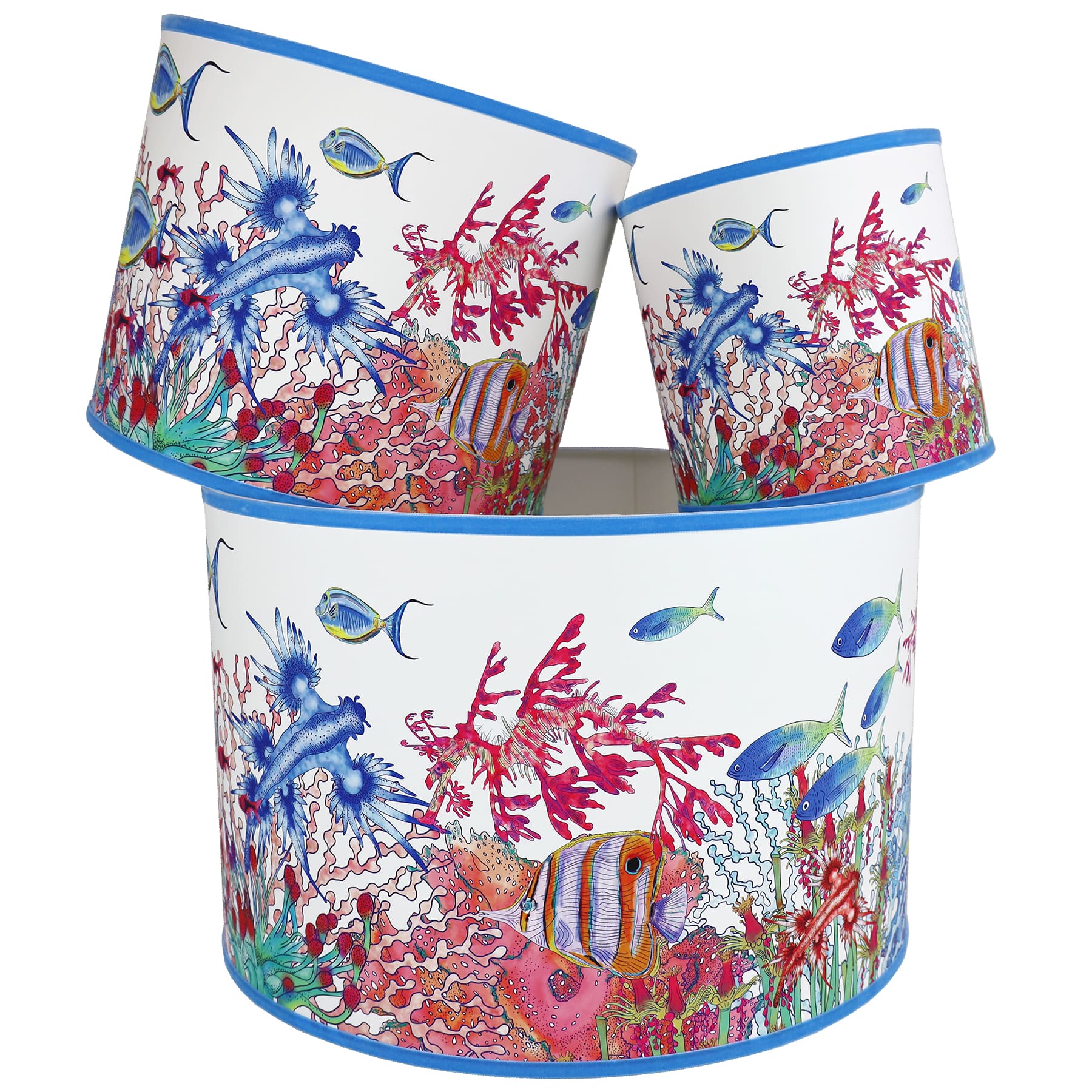 Coral Bay design lampshades in White with blue trim,with various brightly coloured fish swimming amongst the seaweed.The lampshades are shown in a stack of three showing all three sizes.