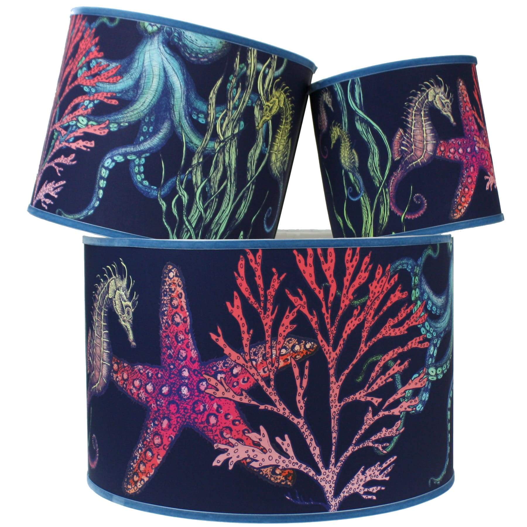 Rainbow Reef Navy Shade With Octopus,Seahorse,Starfish and Seaweed Design in bright colours with a blue trim on the edge of the shade.The lampshades are shown in a stack of three showing all three sizes.