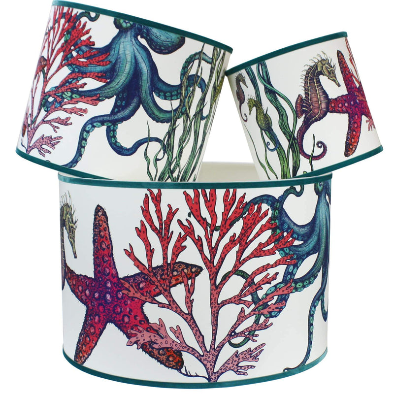 Rainbow Reef White Shade With Octopus,Seahorse,Starfish and Seaweed Design in bright colours with a blue trim on the edge of the shade.The lampshades are shown in a stack of three showing all three sizes.
