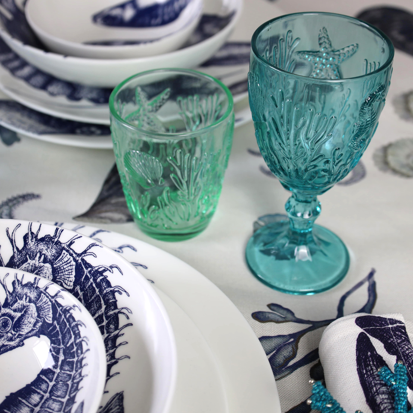 Underwater goblet in teal in a table setting next to one of the underwater tumblers in Green 
