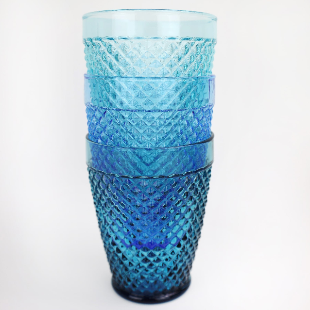 Close up of four stacked cobalt diamond cut tumblers on a table-kitchen and dining