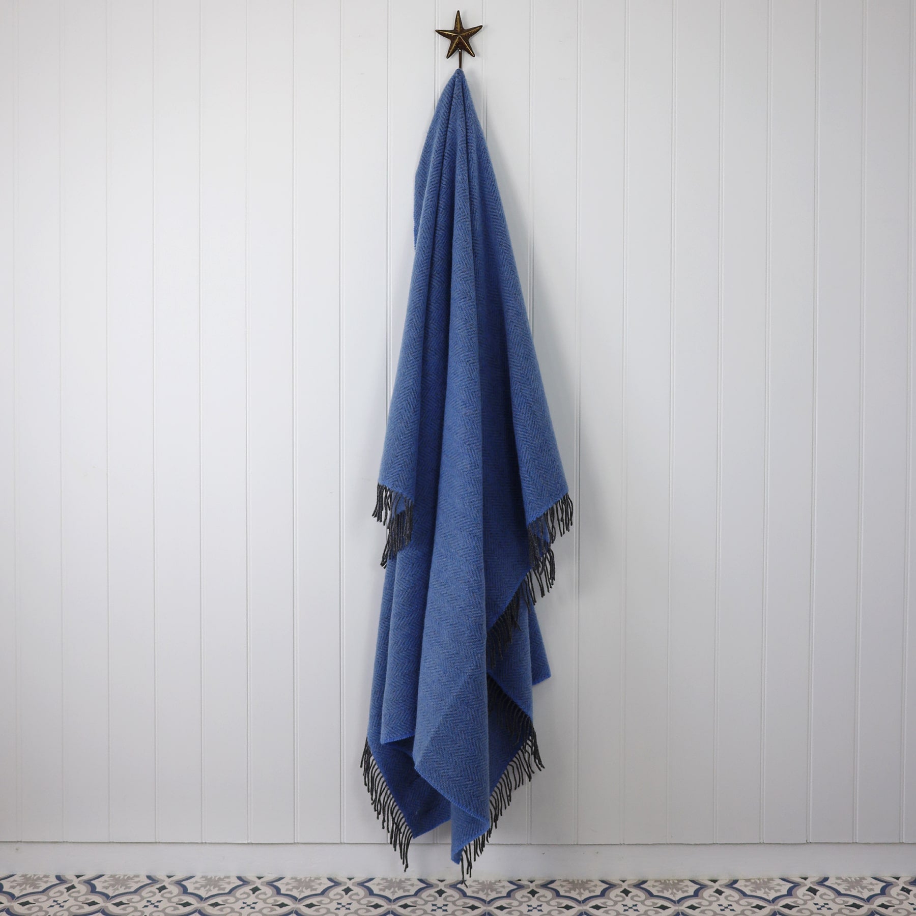 Cashmere Throw Grey Blue Herringbone draped on a Starfish hook against a white tongue and grooved wall