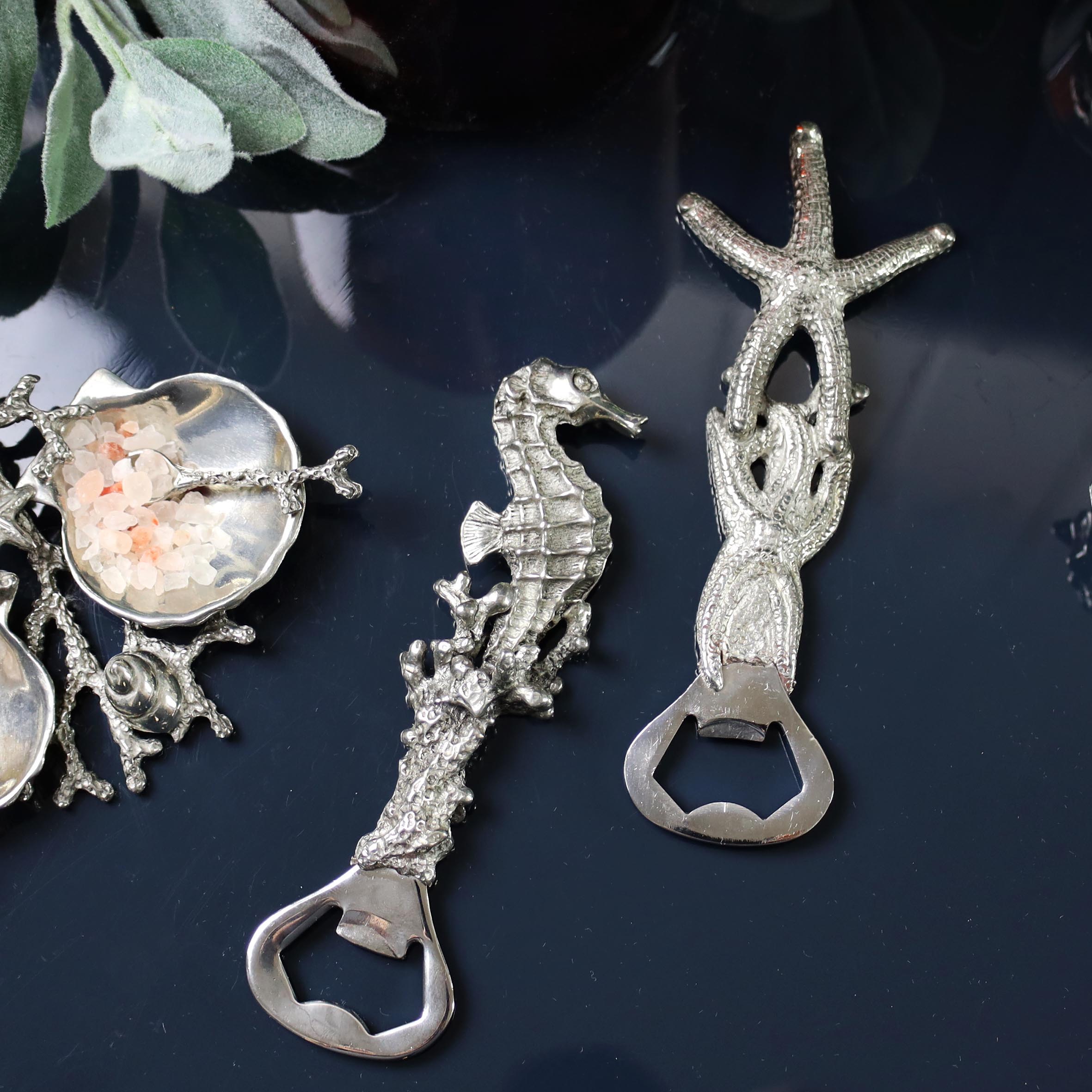 Pewter Seahorse and a Shell  shaped Bottle Opener placed on a table