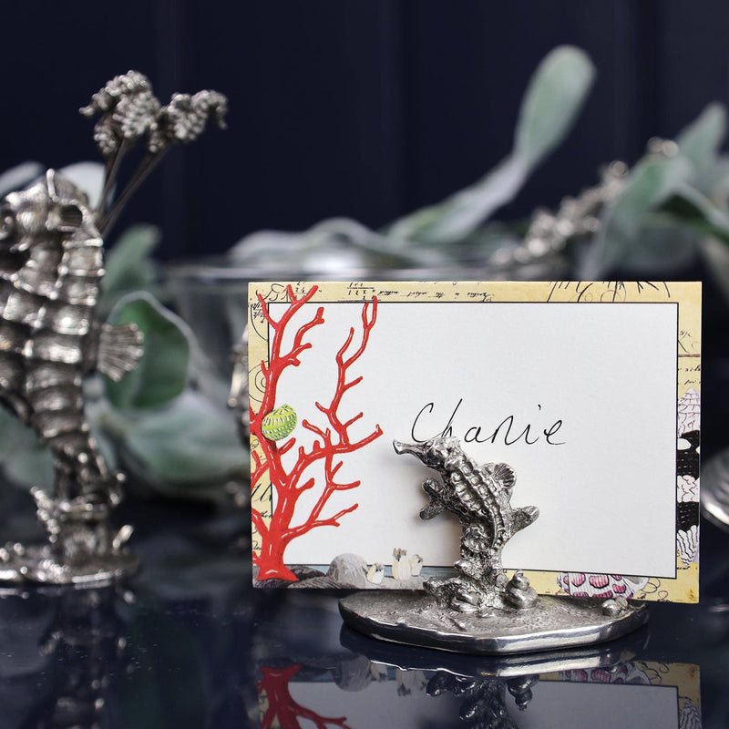 Pewter Coral & Seahorse Card Holder shown holding placecard and other pewter items in the background