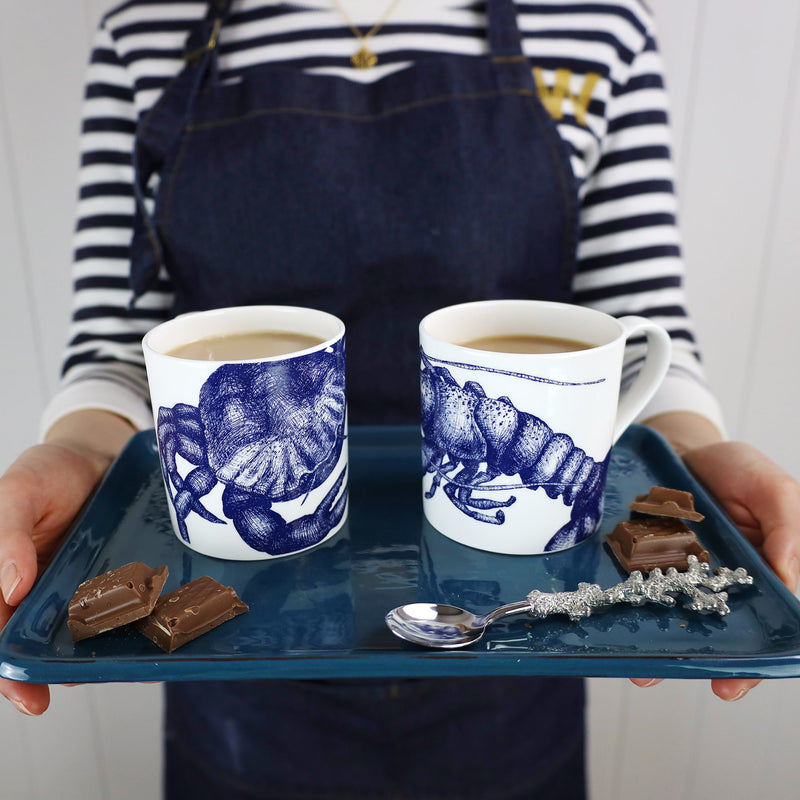 Two Bone china white mugs featuring hand drawn Crab design and the other in the Lobster design in classic Navy on a tray with chocolate and a pewter spoon