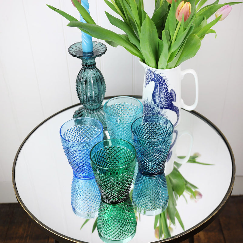 Ariel shot of four diamond cut tumblers on a mirror table,also with a seahorse jug containing tulips