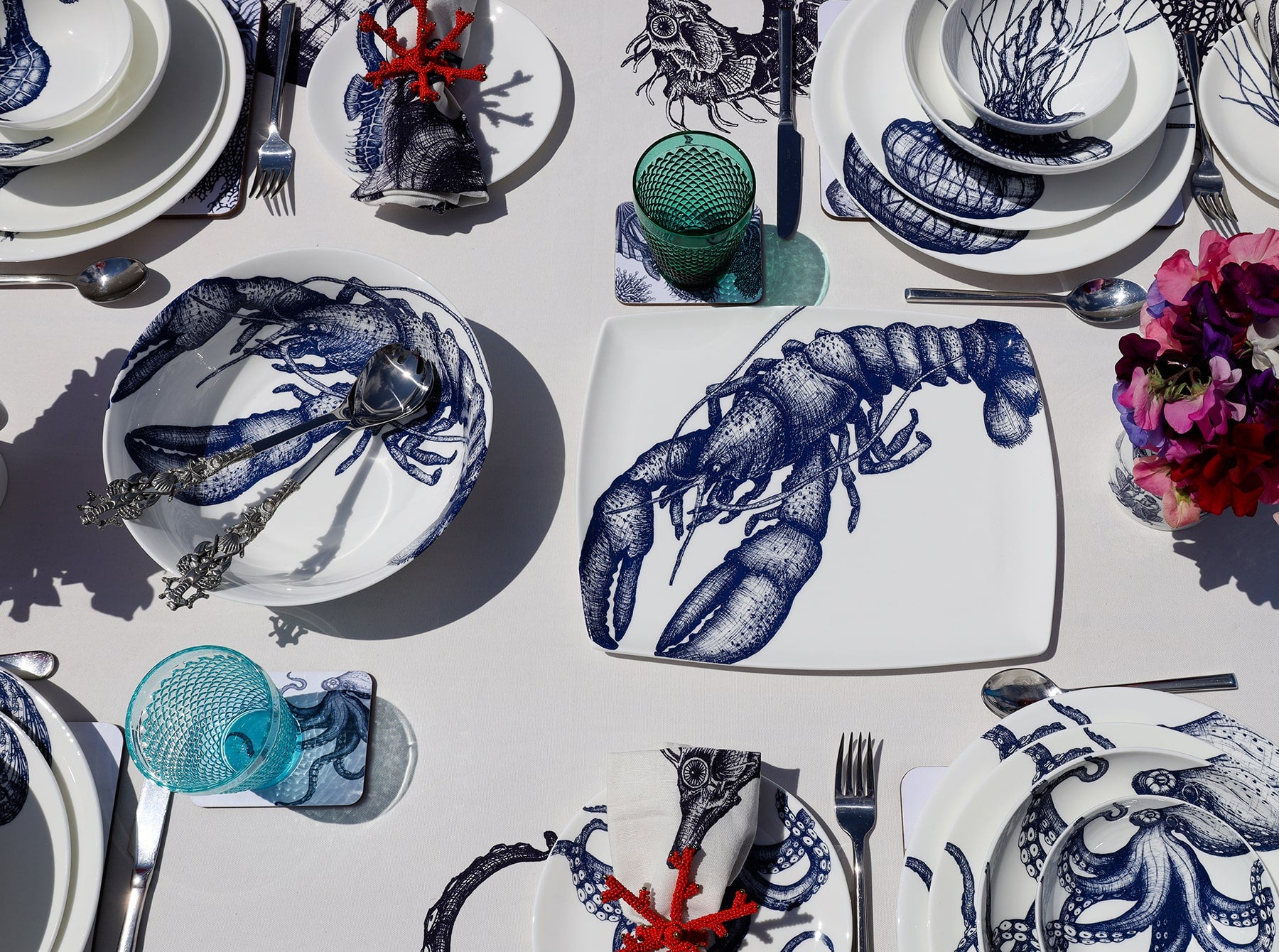 Serving bowl in Bone China in our Classic range in Navy and white in the Lobster design on a white tablecloth.In the bowl are a pair of pewter lobster salad servers,also on the table are other Cream place settings with Dinner plate,side and pasta bowls in Jellyfish and Octopus amongst others