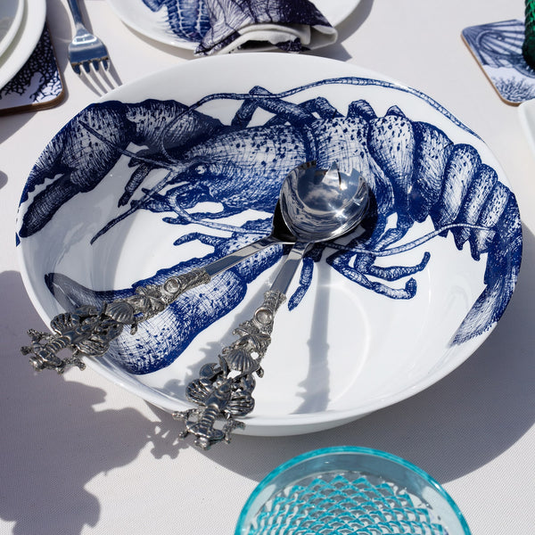 Serving bowl in Bone China in our Classic range in Navy and white in the Lobster design on a white tablecloth.In the bowl are a pair of pewter lobster salad servers,also on the table are other Cream pieces of tableware
