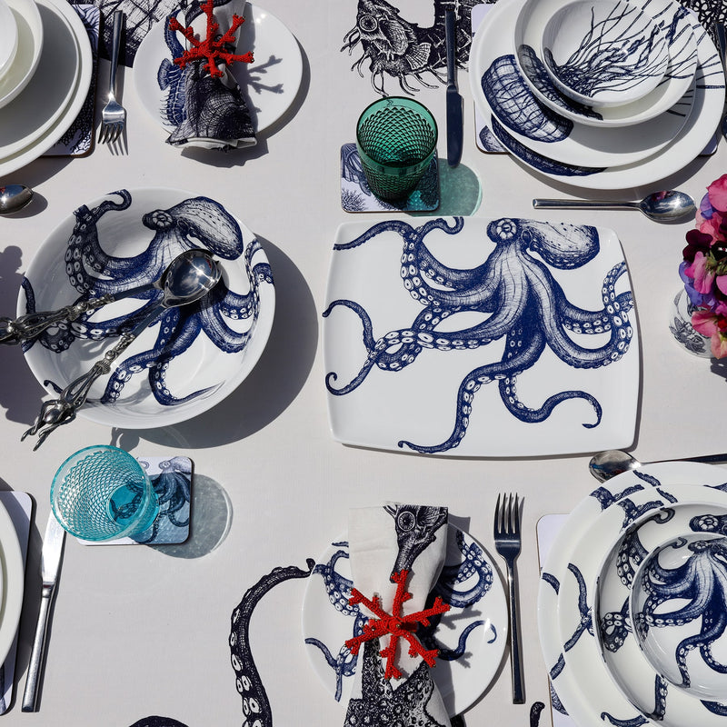 Platter in Bone China in our Classic range in Navy and white in the Octpous design on a white tablecloth .In the background are other place settings in our classic designs and an Octopus serving bowl with serving spoons