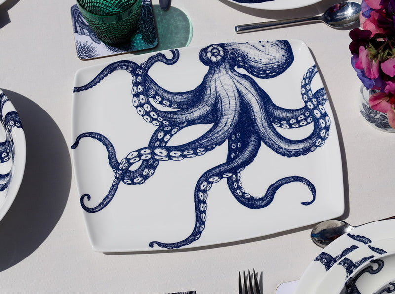 Platter in Bone China in our Classic range in Navy and white in the Octopus design on a white tablecloth placed on a tablemat.In the background are other place settings in our classic designs