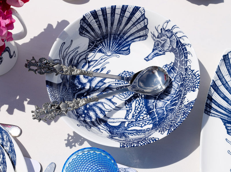 Serving bowl in Bone China in our Classic range in Navy and white in the Seahorse design on a white tablecloth.In the bowl are a pair of pewter lobster salad servers,also on the table are other Cream pieces of tableware