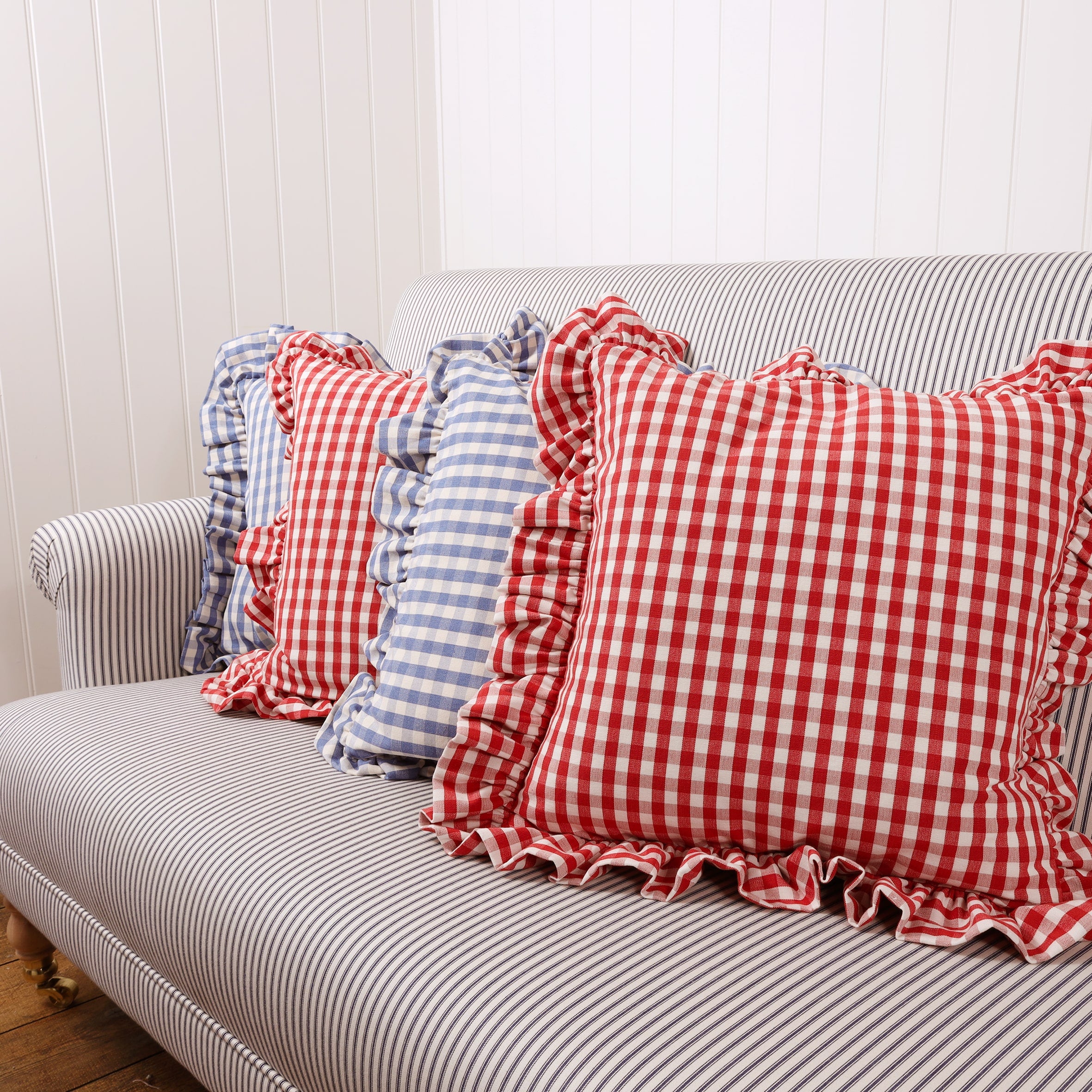 Red Gingham cushions and  blue gingham cushions placed in an alternate row on a navy stripe sofa
