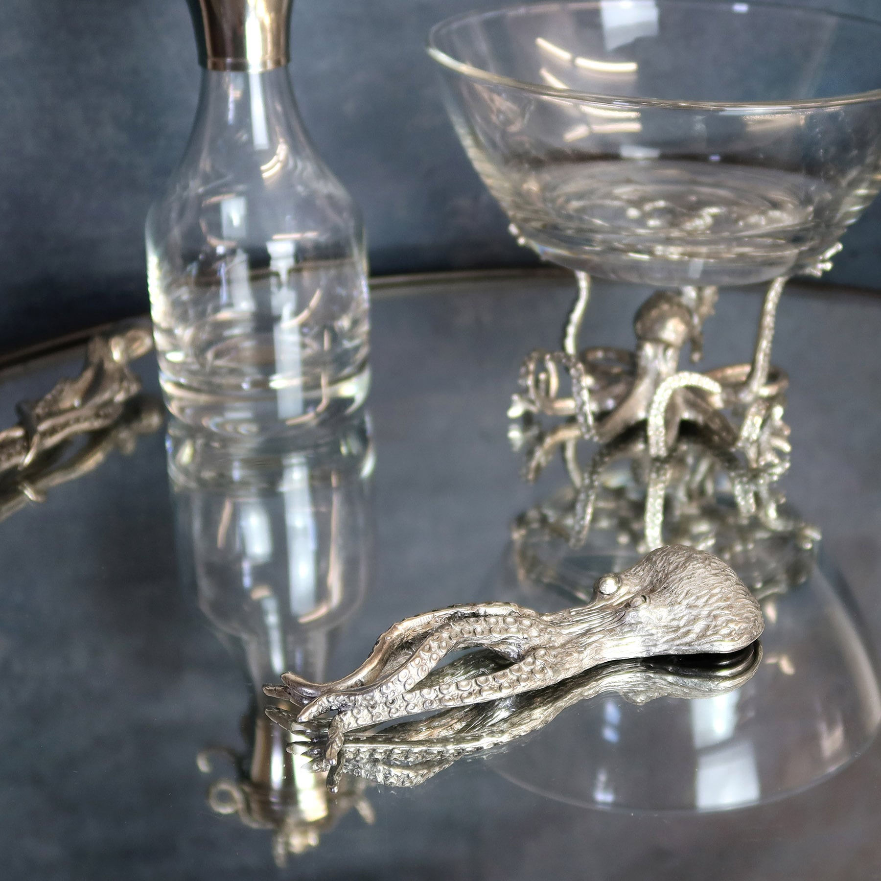 Pewter Octopus Bottle opener on a mirror table in front of  other pewter items 