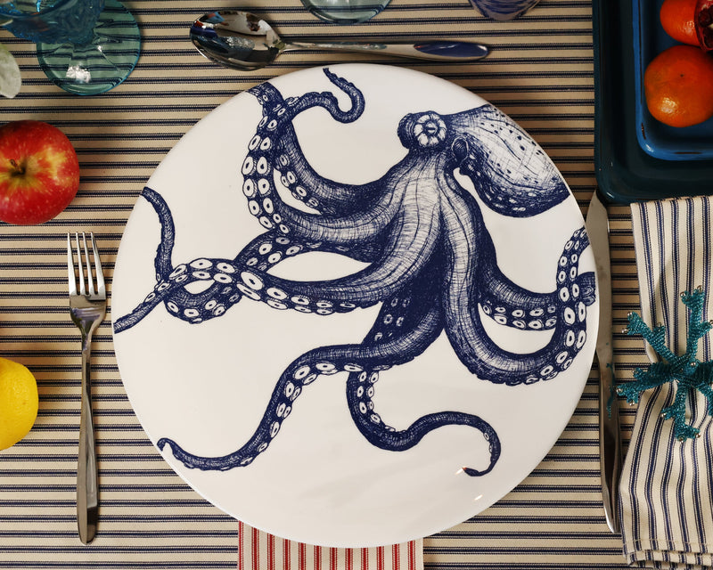 Aerial view of Bone China White plate with hand drawn illustration of our Classic Octopus in Navy on a  dinner plate.Set in place setting with cutlery on a navy stripe tablecloth
