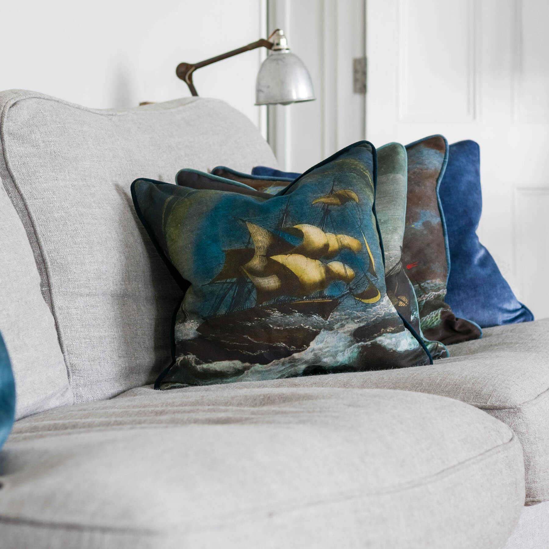 Tornado Cushion Cover ,scene of a billowing sailing ship in rough waters on a sofa with other shipwreck design ciushions.