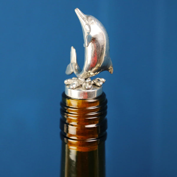 Pewter Dolphin shaped Cork Stopper with body going up placed in the top of a brown wine bottle