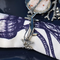 Close up of Pewter Dolphin Napkin Ring on a Jellyfish napkin with other pewter items on the table