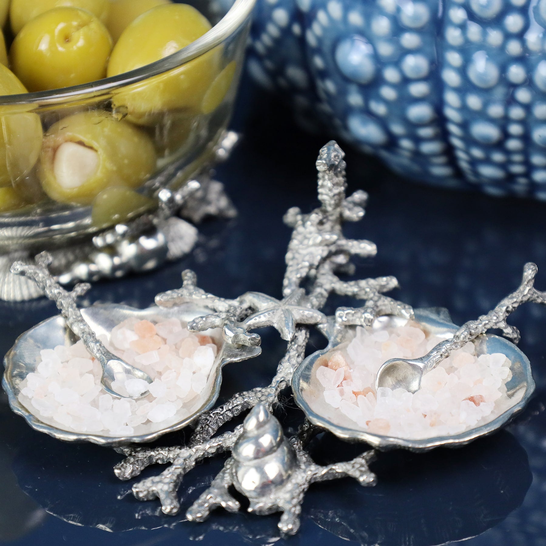 Pewter Shell & Coral Condiment Set  consists of two pewter scallop shaped bowls held together by a sea coral design pewter structure,it has a starfish,tiny seahorse and a shell on the branches and the bowls are holding salt