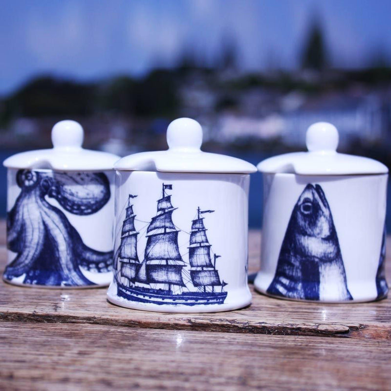 Jam Pots with lid in our classic range in the Mackerel design,Octopus and Packet ship with a space in the lid for a tea spoon,all three are on a wooden table with the harbour's edge in the background