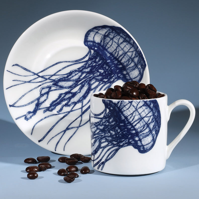 Bone China white espresso cup in hand drawn illustration in our Jellyfish design in Navy with matching saucer.Saucer is standing on its side with the coffee cup in front filled with coffee beans
