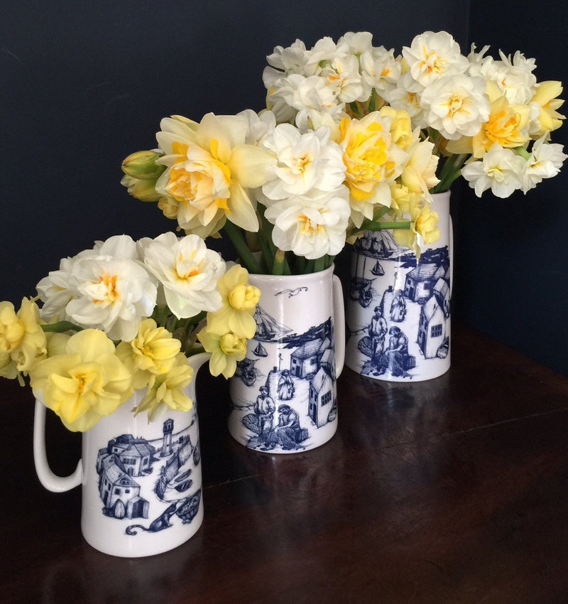 Three Bone China white Jugs with hand drawn illustration of our Harbour scene in Navy.There are three sizes Large,Medium and the small.Each are holding beautiful white and yellow daffodils
