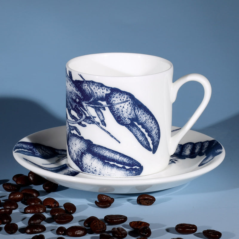 Bone China white espresso cup in hand drawn illustration in our Lobster design in Navy with matching saucer surrounded by coffee beans