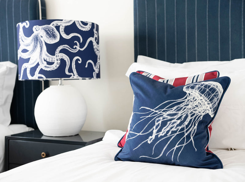 Our Classic Octopus White design on a Navy background on a White lampbase placed on a navy bedside table in between two single beds. One of the beds have our classic designs placed on.