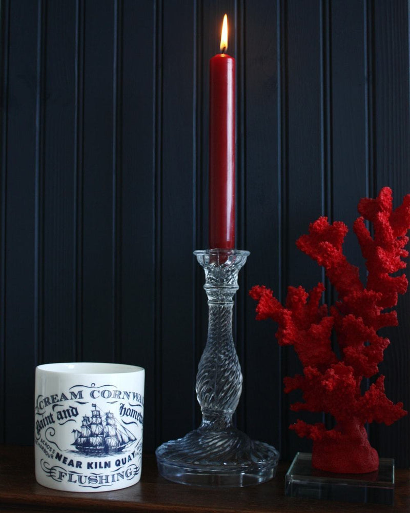 Flushing pint mug on a sideboard next to a clear candlestick and a red coral on a perspex base