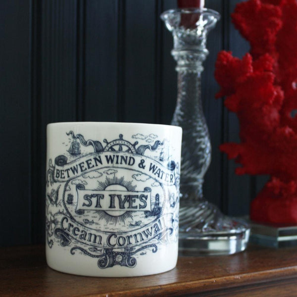 St Ives pint mug on a sideboard next to a clear candlestick and a red coral on a perspex base
