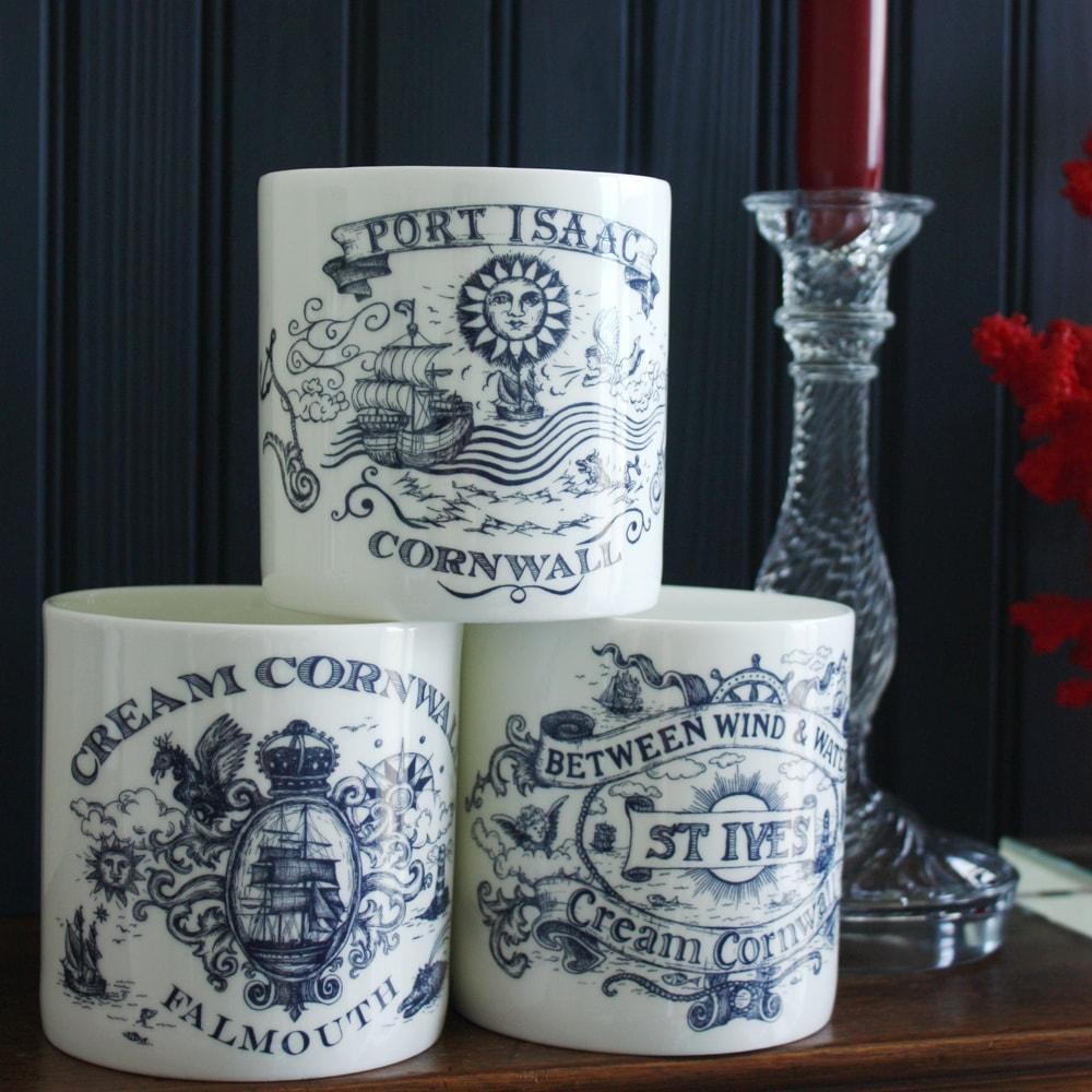 St Ives pint mug on a sideboard in a stack of three pint mugs next to a clear candlestick and a red coral on a perspex base