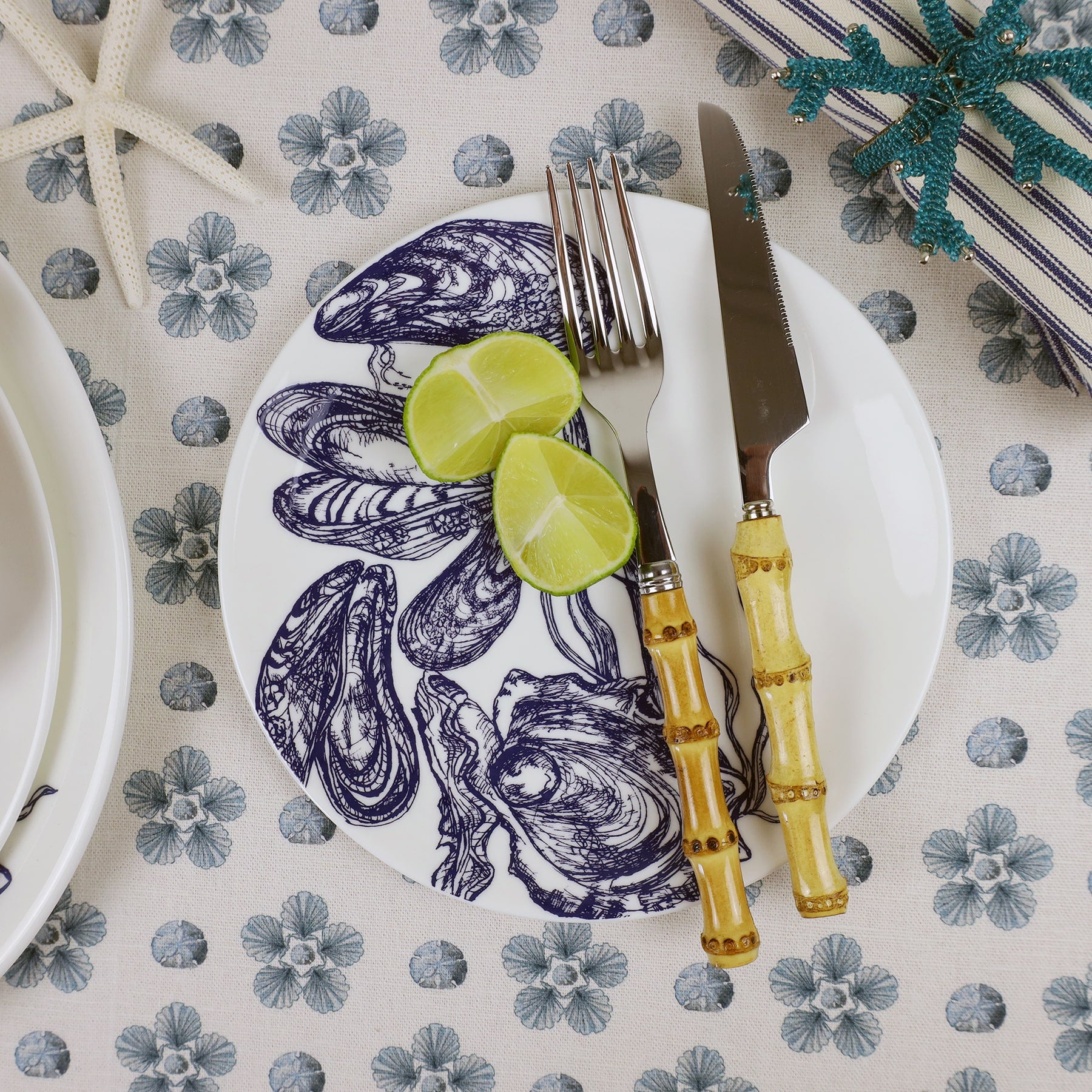 Bone China Large Mussel & Oyster plates with bamboo cutlery and wedges of lime on a tablecloth