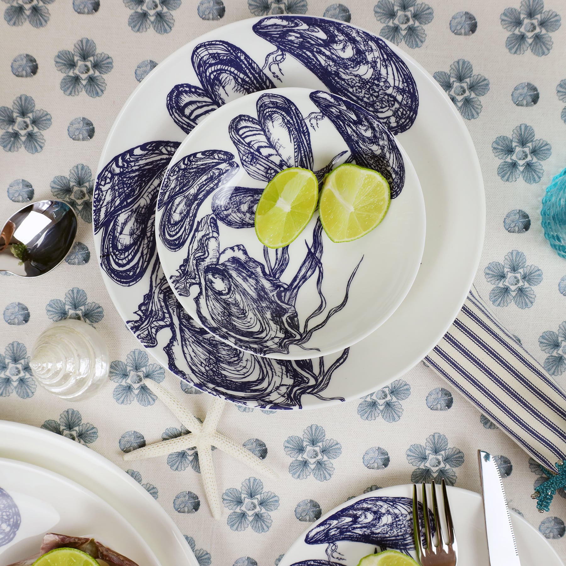Pasta bowl in Bone China in our Classic range in Navy and white in the Mussel design, and a smaller bowl placed inside with a couple of limes.All placed on mini star fabric and other pieces of table decorations and another plate is in the foreground