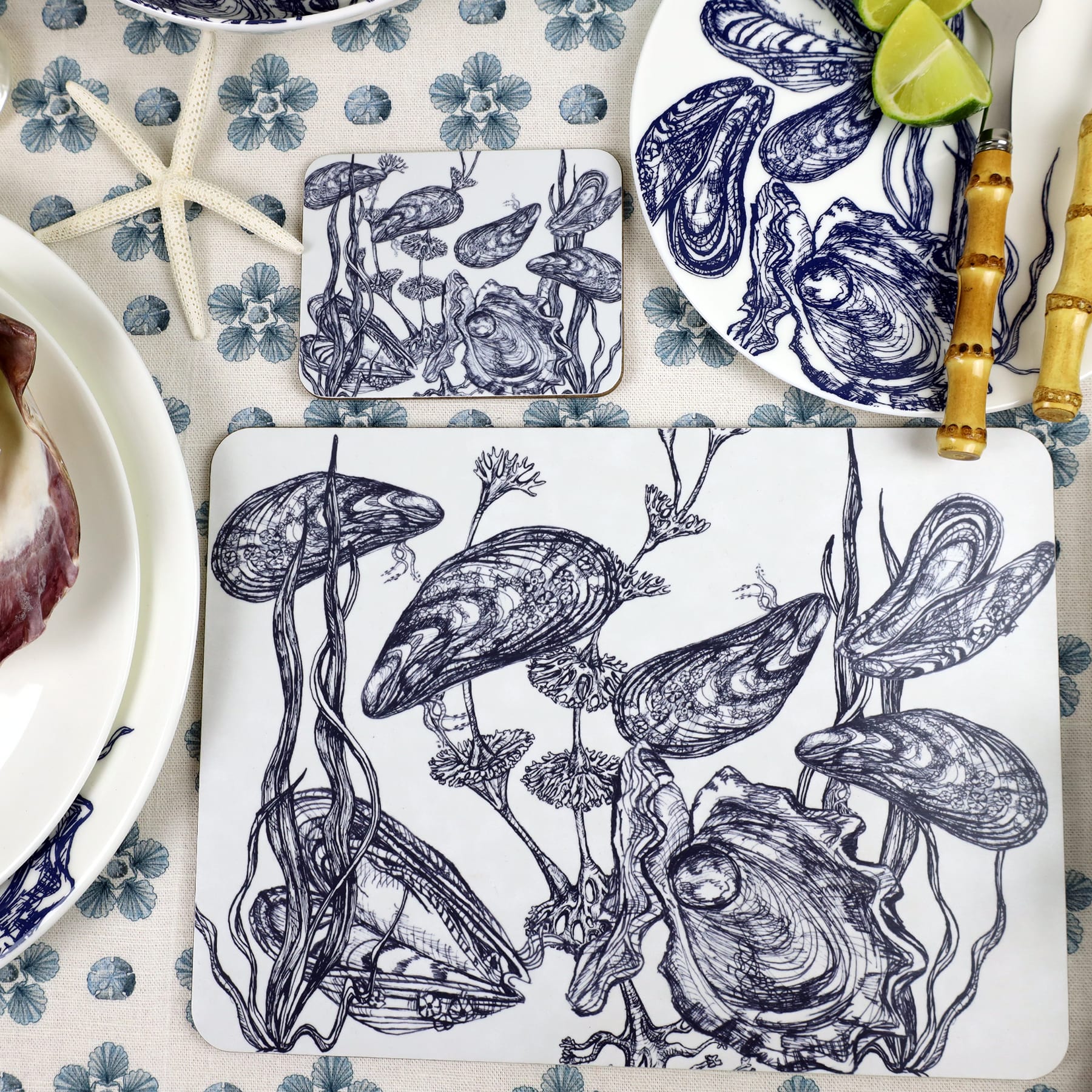Mussel and Oyster Design in Navy on a white Coaster with a matching Placemat on a Seastar printed tablecloth,also on the table are other tableware