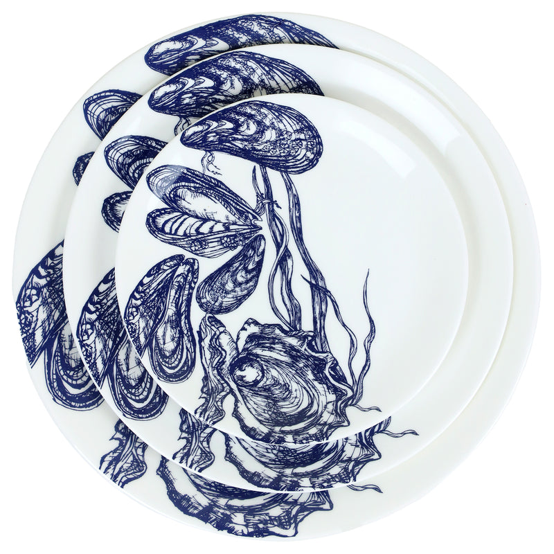 Aerial view of Bone China White plate with hand drawn illustrations of mussels and oysters  in Navy stacked with the dinner plates and side plate