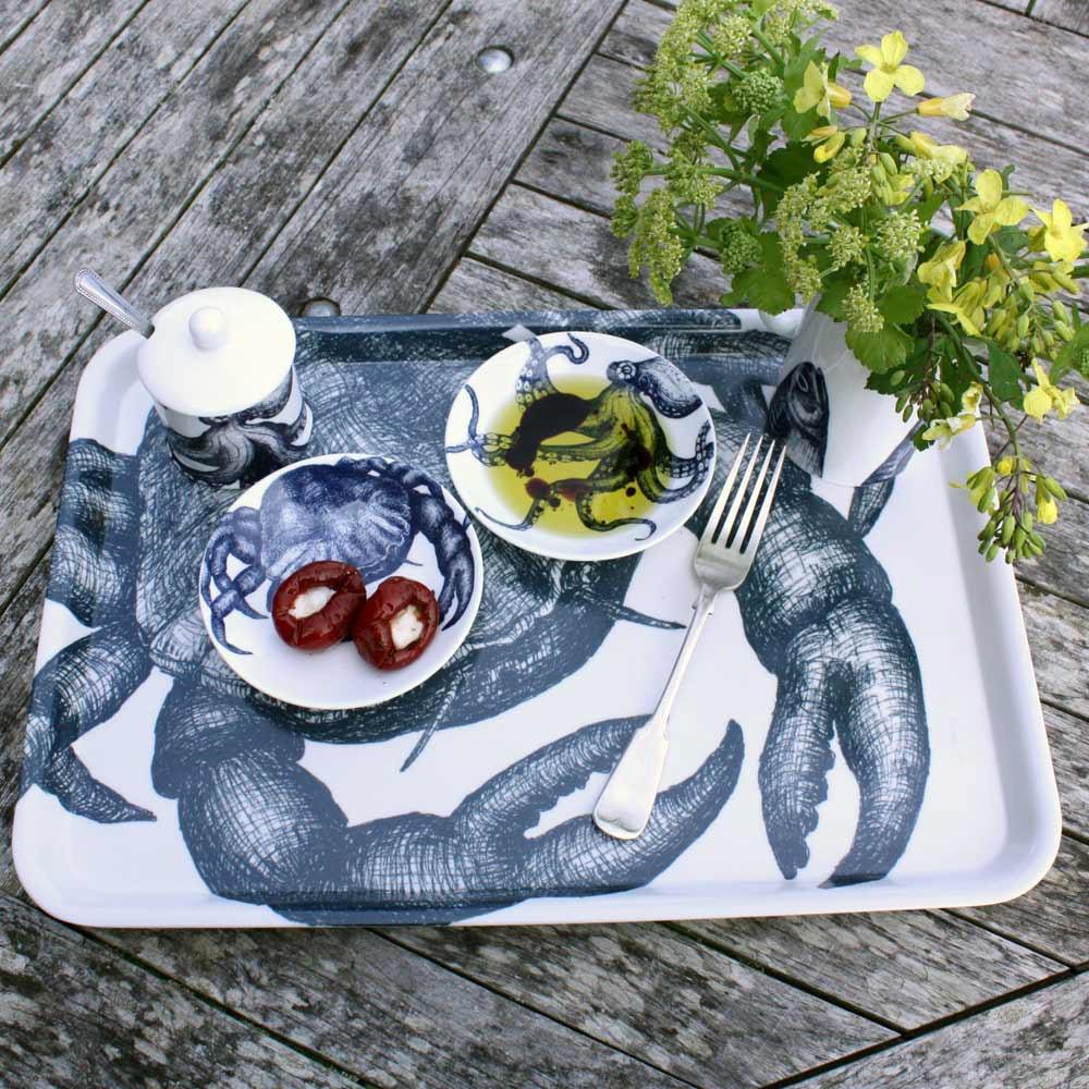 Nibbles bowl in Bone China in our Classic range in Navy and white in the Crab design next to an octopus nibbles bowl with olives.All placed on an Crab Tray with a  jug and jampot,all on a wooden table