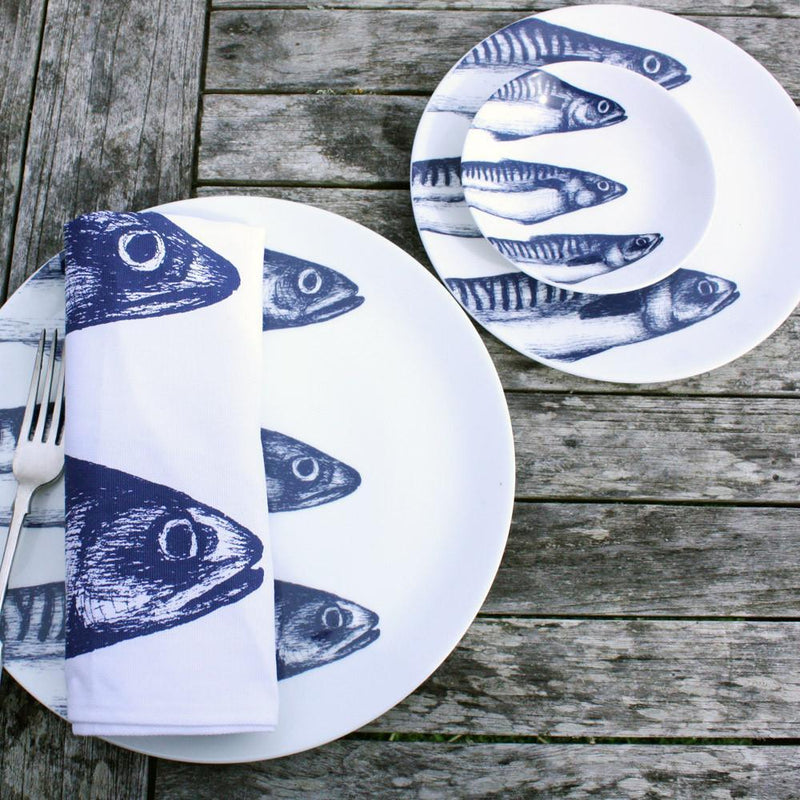 Nibbles bowl in Bone China in our Classic range in Navy and white in the Mackerel design next to a matching plate on a wooden table.On the plate is a folded napkin,there are matching plates on the table