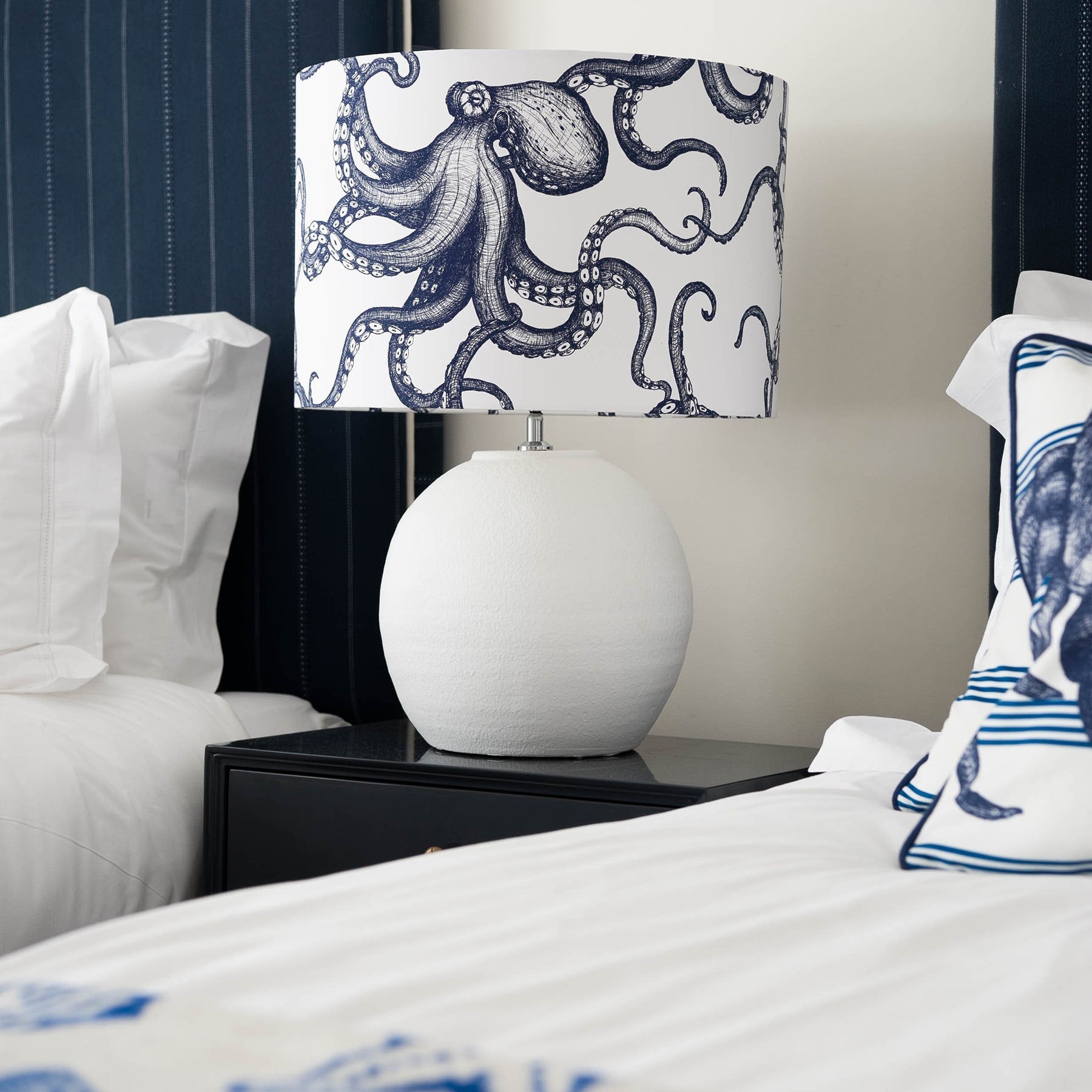 Our Classic Navy Octopus design on a white background on a white lampbase on a side table between two single beds.