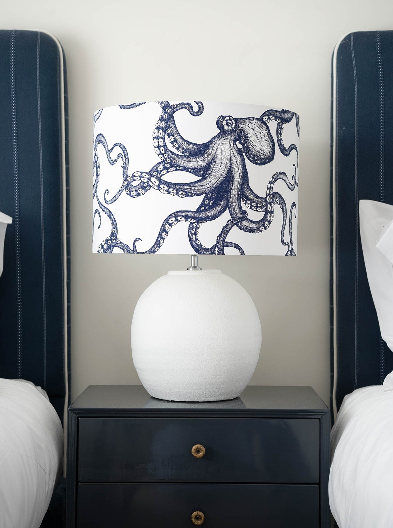 Our Classic Navy Octopus design on a white background on a white lampbase on a side table in between two single beds 