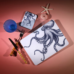 Octopus Design in Navy on a white Coaster with a matching Placemat.On the table is a bamboo cutlery set and a blue coloured glass