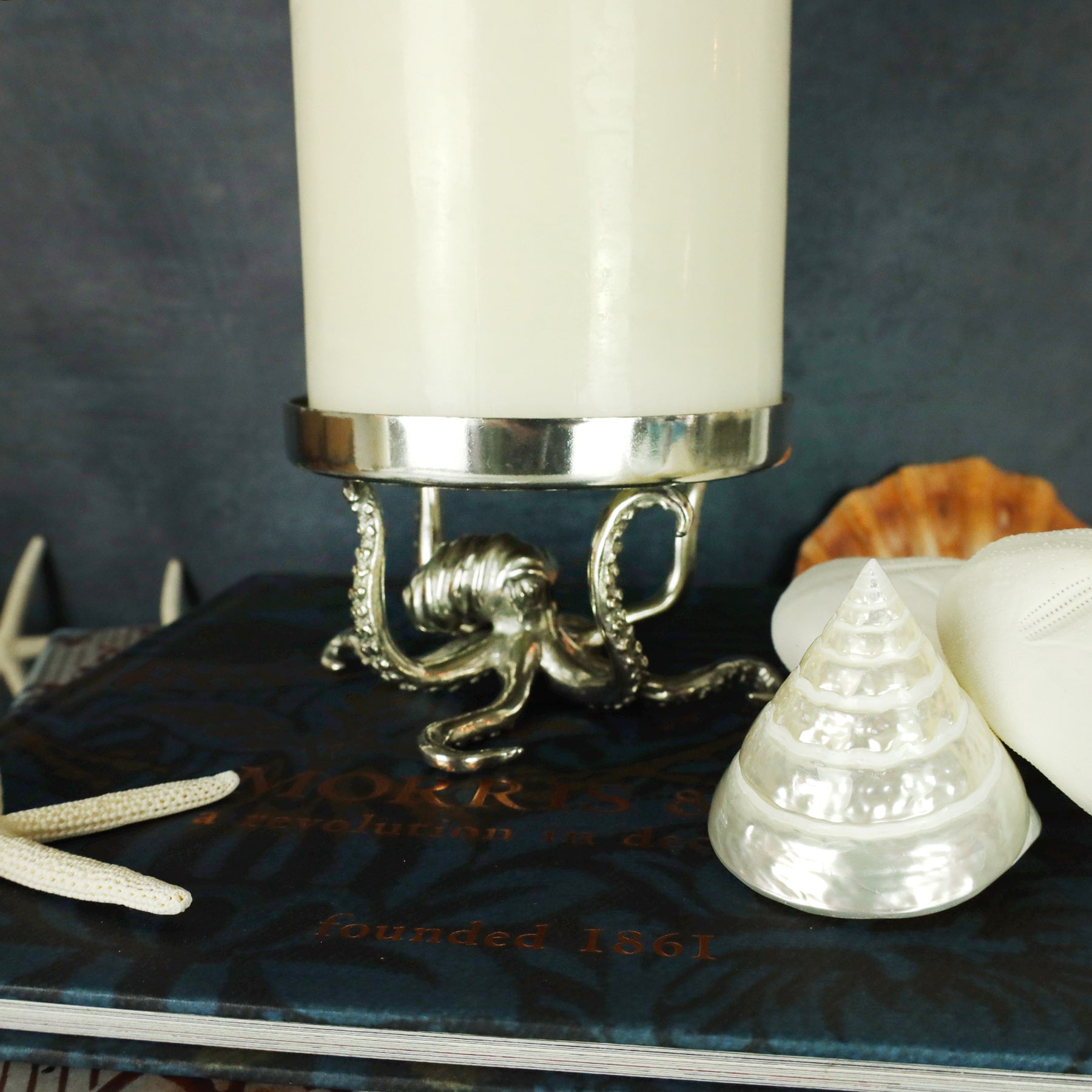 Close up of large Pewter Candle Holder with Octopus Base placed on a table next to some shells