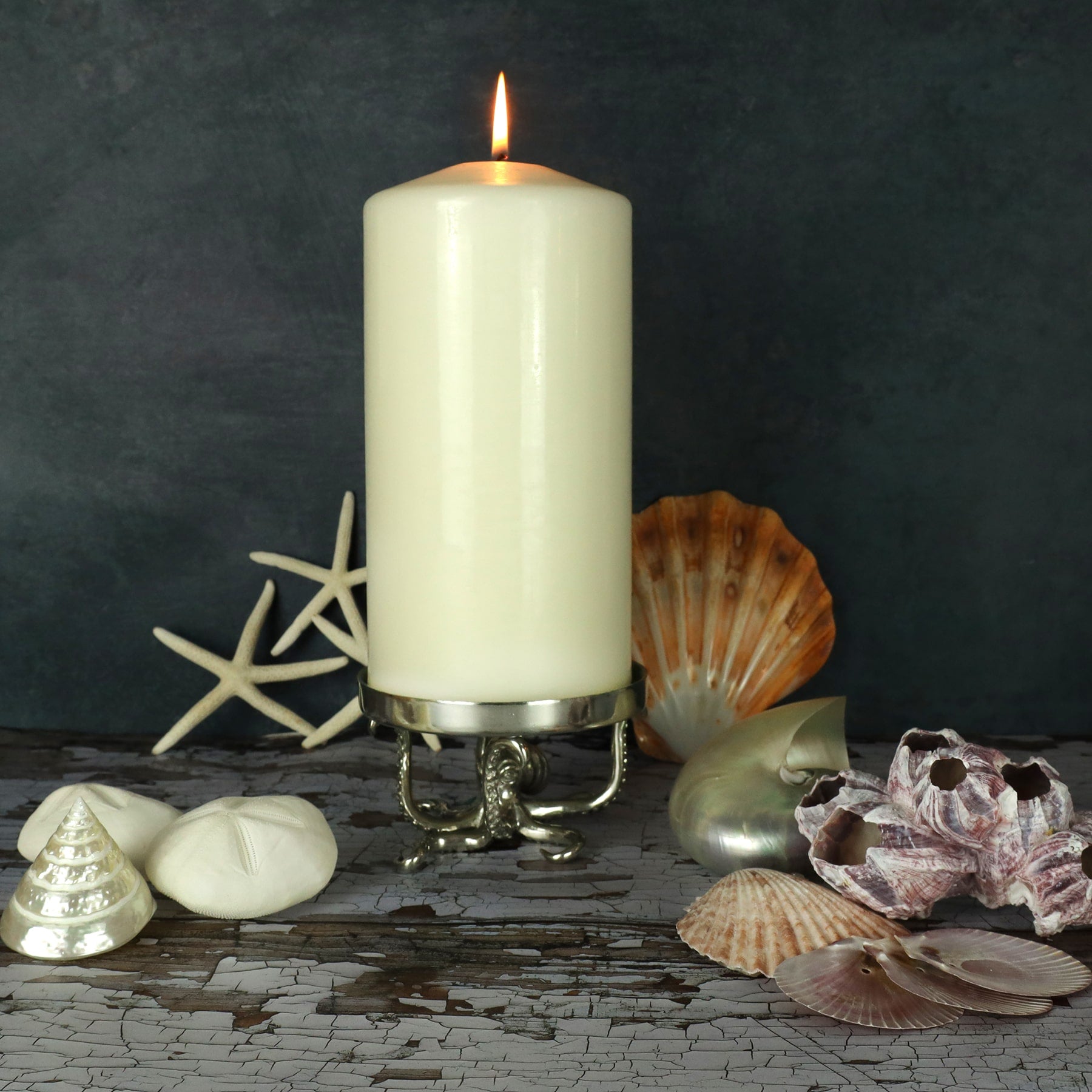 Close up lifestyle shot of large Pewter Candle Holder with Octopus Base on a table with shells decorating the table top