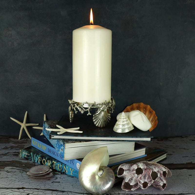 Pewter large candle holder featuring shells and coral  placed on a table with books and shells
