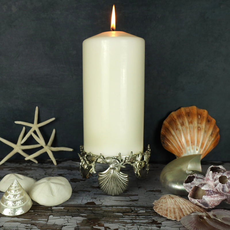 Pewter large candle holder featuring shells and coral placed on a table with shells