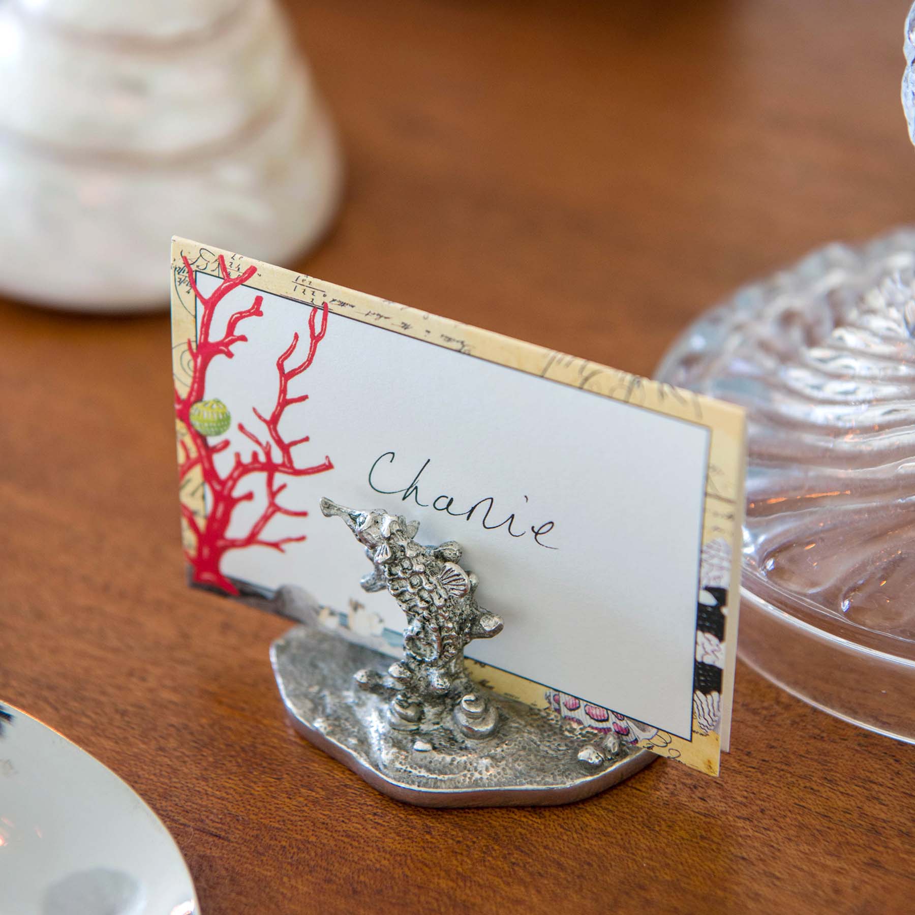 Pewter Coral & Seahorse Card Holder shown holding placecard and other items on a table