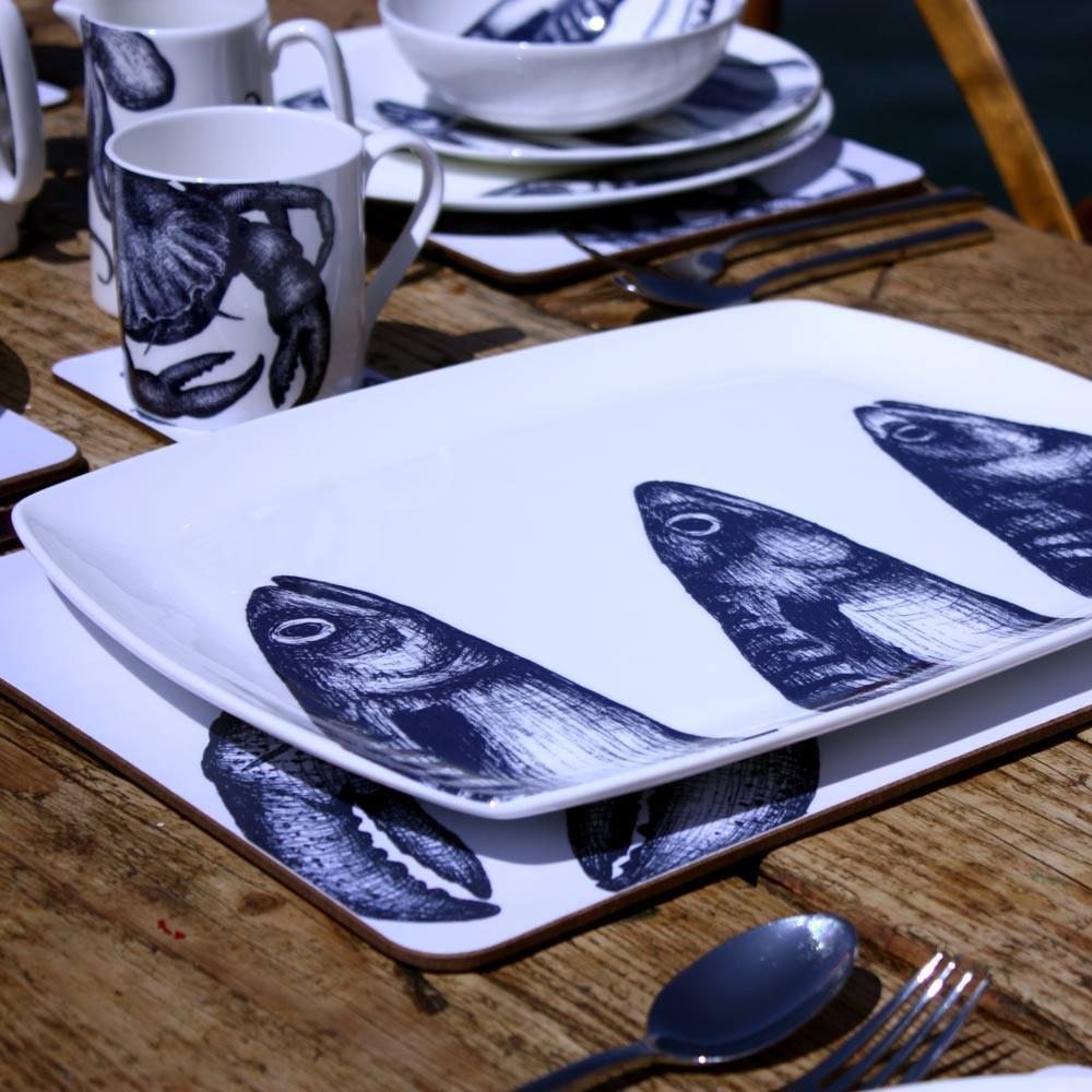 Platter in Bone China in our Classic range in Navy and white in the Mackerel design on a outdoor wooden table placed on a tablemat.In the background are other place settings in our classic designs