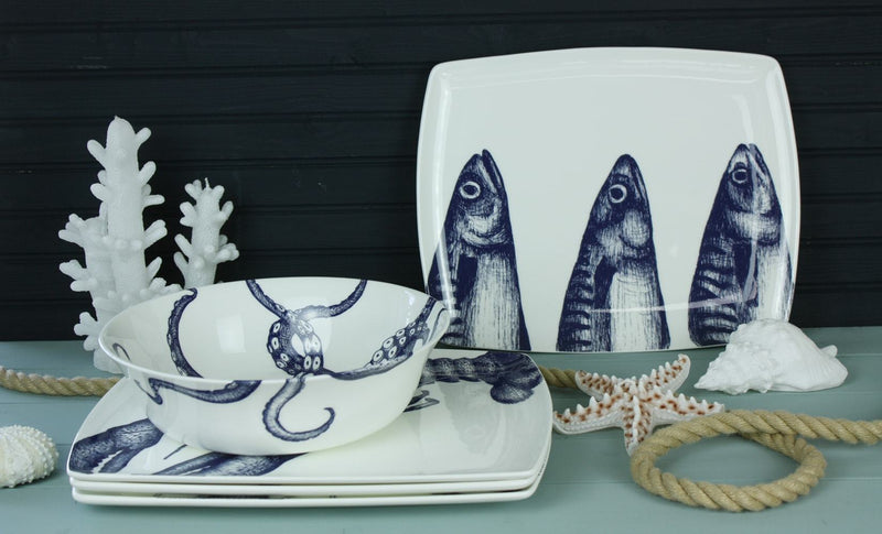 Platter in Bone China in our Classic range in Navy and white in the Mackerel design on its side.In front are matching side plates and bowls with various candles on the table with a winding rope on the table