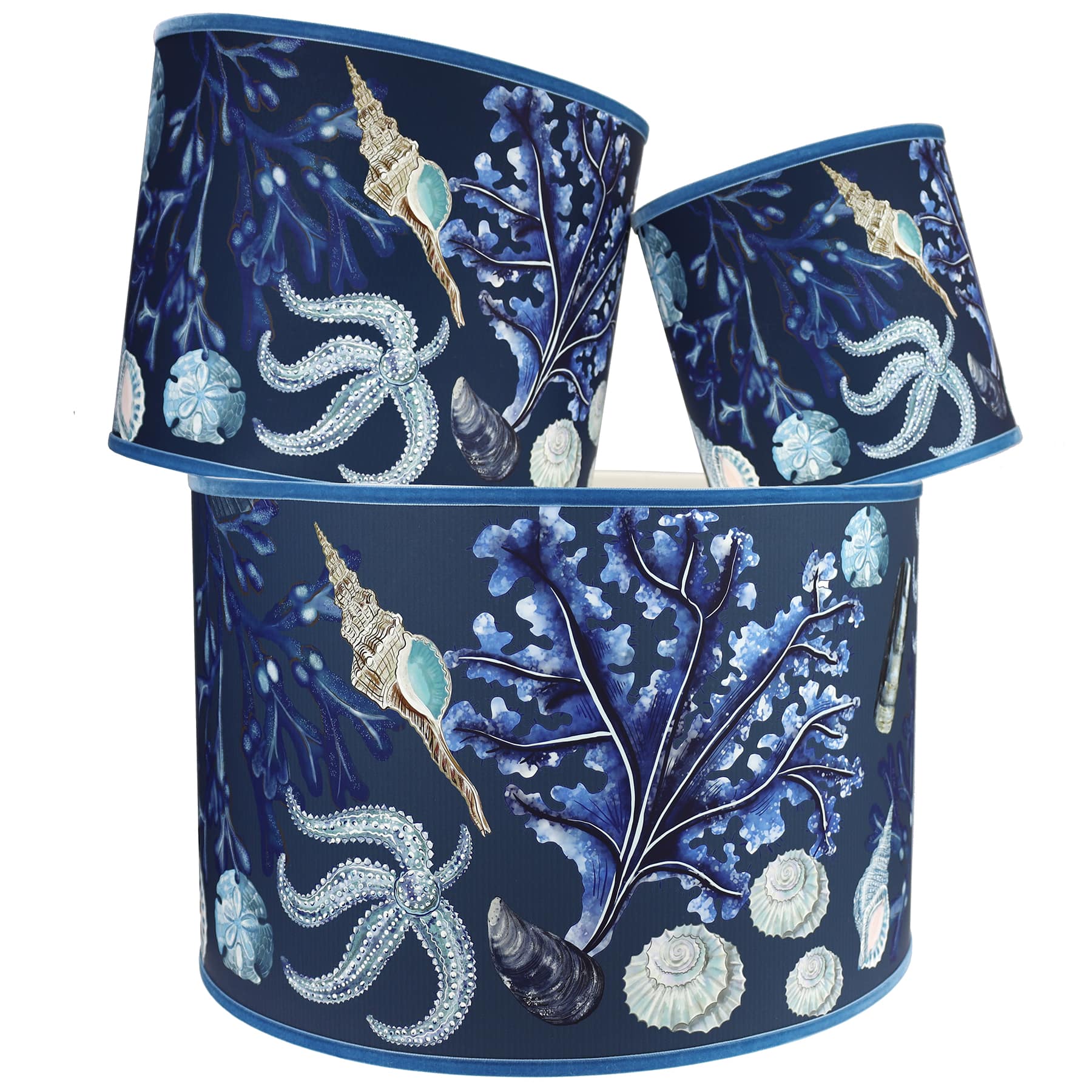 Rockpool Navy Shade With Shells,Seaweed,Sand dollars and Starfish Design in blues/browns with a blue trim on the edge of the shade.The lampshades are shown in a stack of three showing all three sizes.
