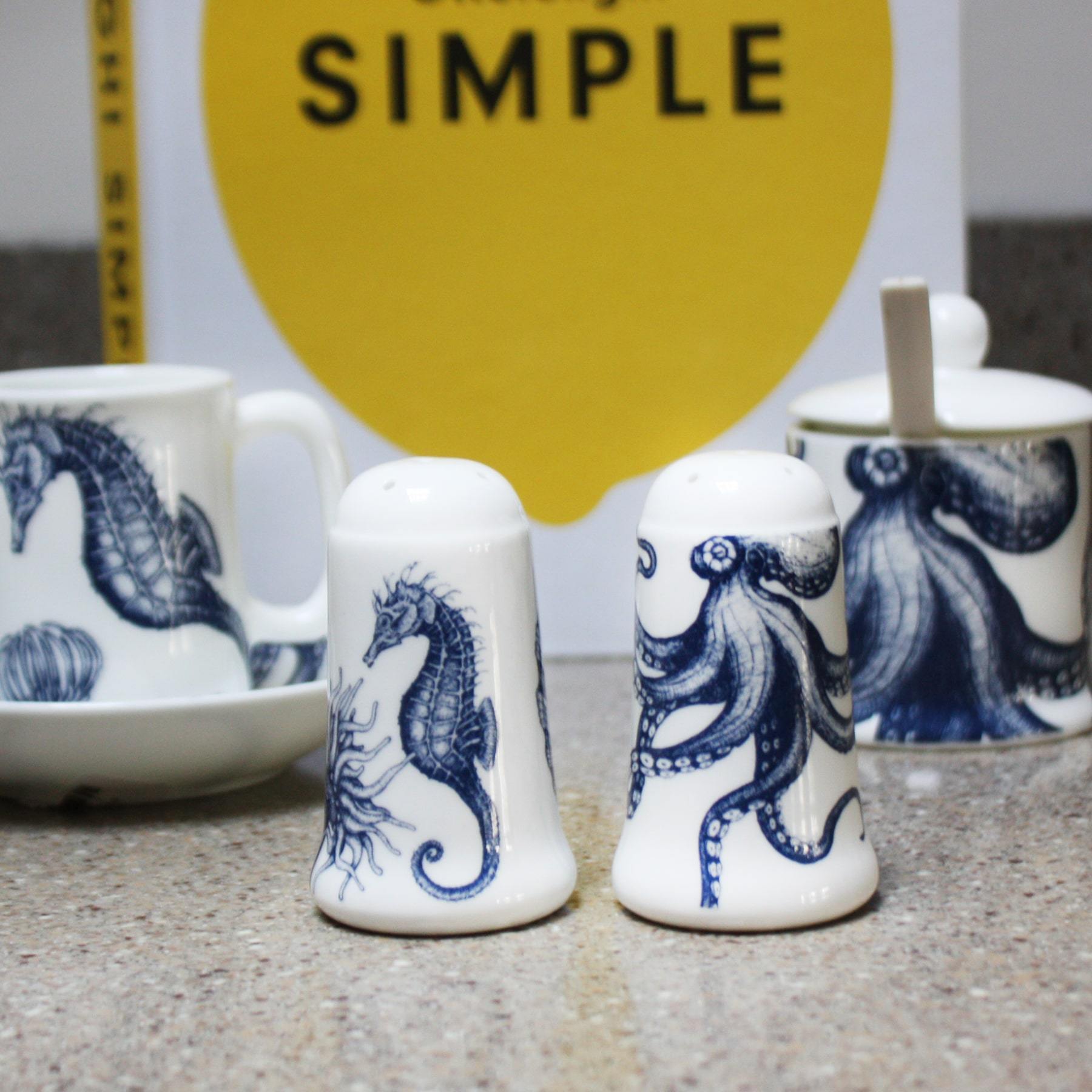 Bone china salt an pepper pots in our classic navy and white.Salt has seahorse, shell and an anenome on and the pepper has an octopus.These are both placed in from of an octopus Jam pot and a seahorse jug,in the background you can see a cookbook