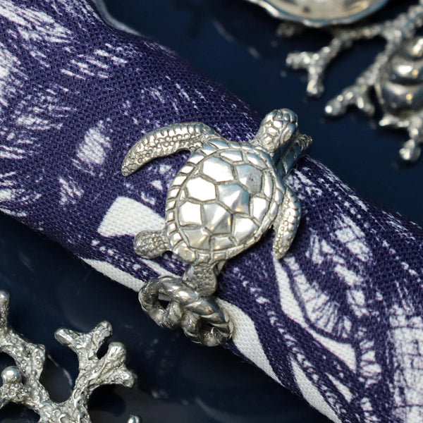 Close up of Pewter Turtle Napkin Ring,which is part of the Sea Animal Napkin ring set on a Jellyfish napkin with other pewter items on the table