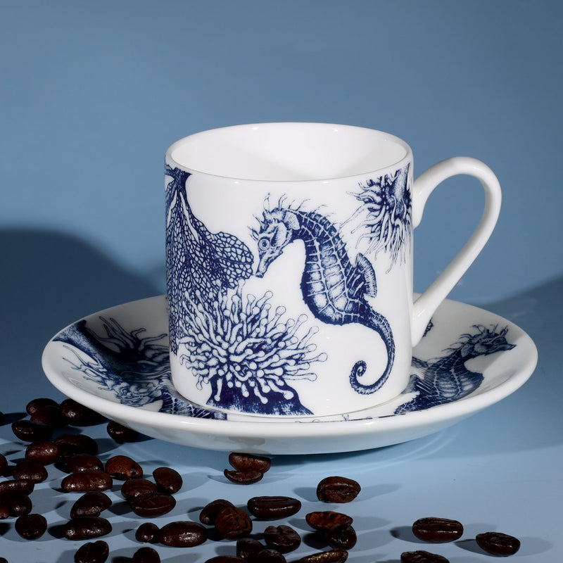 Bone China white espresso cup in hand drawn illustration in our Seahorse design in Navy with matching saucer surrounded by coffee beans